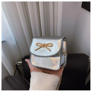 Détail du sac bandoulière argenté pour fille avec nœud doré et chaîne élégante