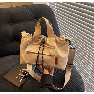 Détail du sac seau en toile beige avec cordon de serrage, poche à pression et poignée