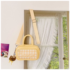Close-up of yellow plaid kids shoulder bag with cute brown teddy bear plush charm