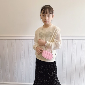 Girl wearing pink quilted chain shoulder bag with diamond bow sweater and sequin skirt