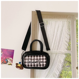 Close-up of kids checkered crossbody bag with cute plush bear charm on window frame