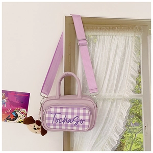 Close-up of small purple checkered kids bag with dog plush charm and adjustable strap
