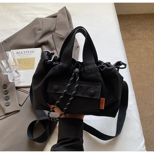 Détail du sac seau noir à cordon avec étiquette tissée orange et bandoulière