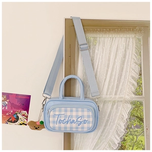 Detail of light blue checkered kids handbag with bear charm and adjustable strap