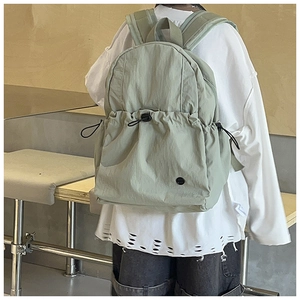 Detailed view of light green waterproof nylon school backpack with drawstring side pockets