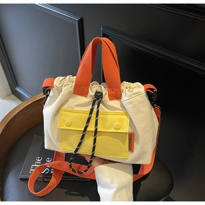 Détail du sac seau en toile contrastée avec poignée et bandoulière orange vif élégante
