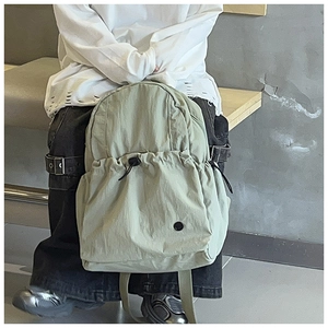 Detailed view of the light green backpack featuring a front drawstring pocket and black buckle