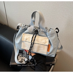 Détail du sac seau en toile bleu clair avec cordon de serrage et poche contrastante