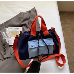 Détail du sac seau en toile color-block avec poignées orange et cordon de serrage