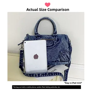 Detail shot showing the large capacity of a blue denim biker bag compared to an iPad mini