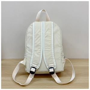 Rear view of minimalist cream nylon backpack with padded adjustable straps and top handle