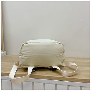 Close-up of the reinforced rectangular base and durable canvas straps on the beige backpack