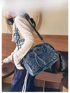 Detail shot of vintage denim shoulder bag showing silver studs and biker-style zippers