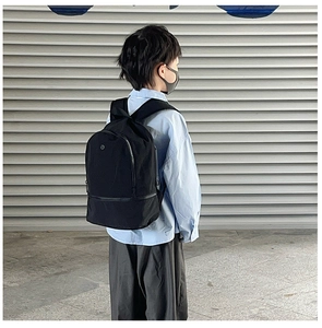 Outdoor shot of a black minimalist multi-pocket kids backpack with front zipper detail