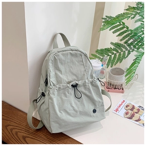 Detail view of water-resistant green nylon backpack with drawstring pocket and side straps