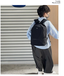 Rear view of a black nylon kids backpack showing straps and size on a child model