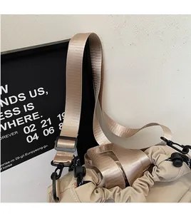 Detail of adjustable black drawstring buckle and wide woven strap on beige bucket bag