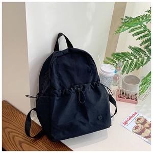 Detail of black nylon backpack with drawstring front pocket and textured fabric finish