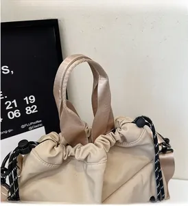 Detailed close-up of beige drawstring bucket bag with durable nylon handles and buckle