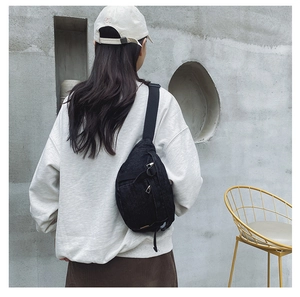 Vue détaillée d'un sac de poitrine en denim noir avec sangle réglable et fermeture éclair métal