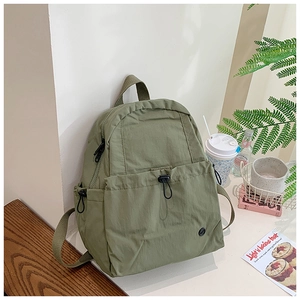 Close-up of olive green school backpack with drawstring pocket and durable nylon texture