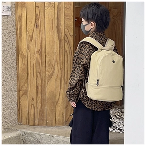 Side view of kid wearing minimalist light beige nylon backpack with large capacity