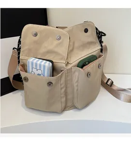Detail of beige canvas bucket bag with multi-pocket design and metal snap buttons