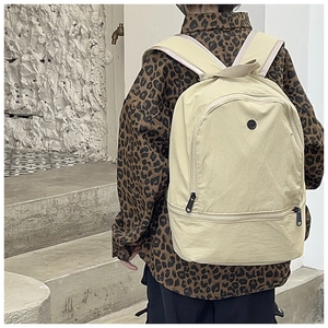 Detail of minimalist beige nylon backpack with separate bottom zipper compartment for kids