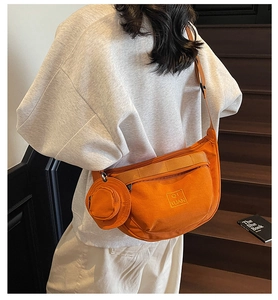 Détail du sac bandoulière en toile orange avec un petit porte-monnaie rond