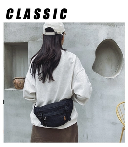 Vue arrière du sac bandoulière en denim noir porté par un mannequin sur mur