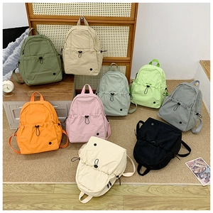 Detail view of eight colorful minimalist nylon school backpacks in a home setting