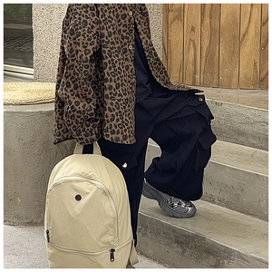 Minimalist beige canvas backpack with black zippers shown in a trendy street style scene