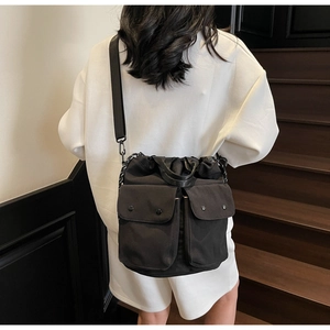 Detail view of a black tactical drawstring bucket bag with dual snap pockets and woven cords