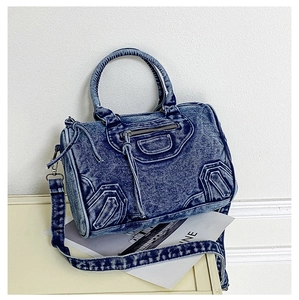 Close-up of vintage blue denim bag with biker style zippers and decorative leather pulls