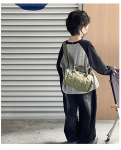 Olive green kids cylinder bag with adjustable strap worn as a stylish crossbody bag
