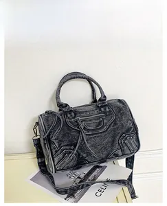 Detail of black acid wash denim biker bag with braided handles and silver hardware