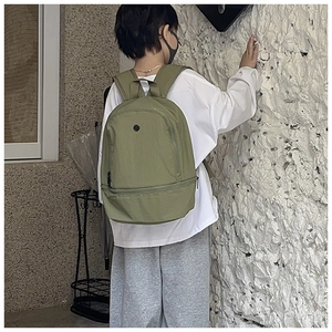 Rear view of a sage green nylon kids backpack shown on a model for size and scale