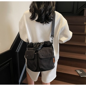Detail of black utility bucket bag showing drawstring closure and front cargo pockets