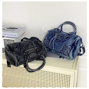 Detail of washed denim cylinder bags in grey and blue with moto-style zippers