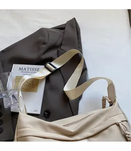 Detail of adjustable wide canvas shoulder strap on a cream minimalist crossbody bag