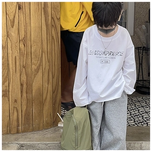 Close-up of olive green backpack straps and white printed sweatshirt for kids
