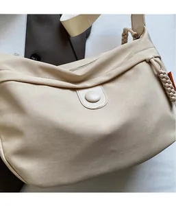 Detail of minimalist beige canvas hobo bag showing lightweight fabric and strap details