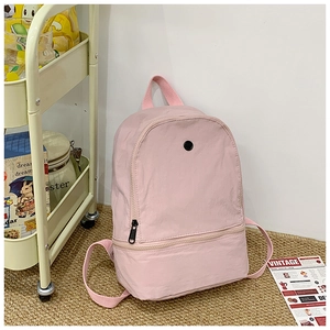 Detailed close-up of a pink minimalist kids backpack with dual zippers and storage compartments