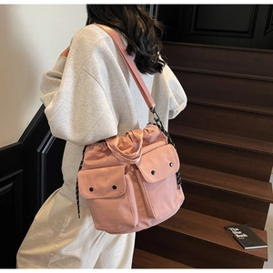 Pink canvas multi-pocket bucket bag with drawstring closure and wide shoulder strap