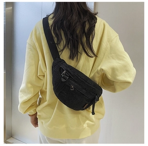 Détail du sac de poitrine en denim noir avec fermetures éclair sur le modèle