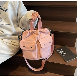 Detail of pink nylon drawstring bucket bag featuring functional cargo pockets and wide strap