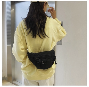 Détail du sac de poitrine en denim noir avec sangle réglable sur sweat jaune