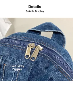Detail of blue denim backpack showing two-way metal zipper and top handle strap