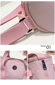 Close-up of pink cylinder shoulder bag featuring black hardware and branded logo patch