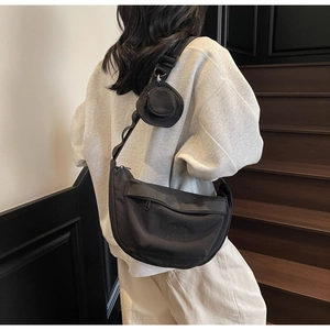 Détail d'un sac bandoulière demi-lune en toile noire avec large sangle réglable sur modèle